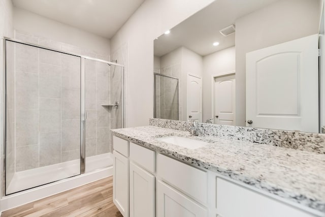 bathroom featuring vanity, wood-type flooring, and a shower with door