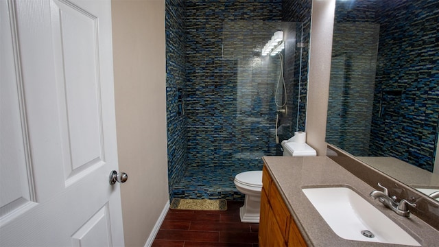 bathroom featuring a tile shower, vanity, and toilet