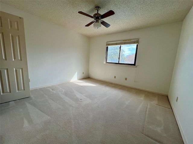 spare room featuring a textured ceiling, carpet, a ceiling fan, and baseboards