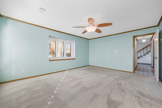 empty room featuring light carpet, ceiling fan, ornamental molding, and a textured ceiling