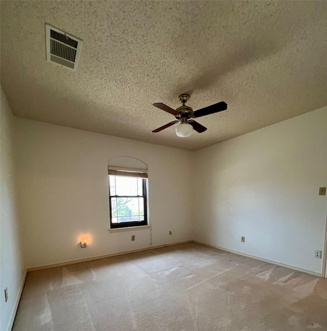 empty room featuring baseboards, visible vents, light colored carpet, ceiling fan, and a textured ceiling