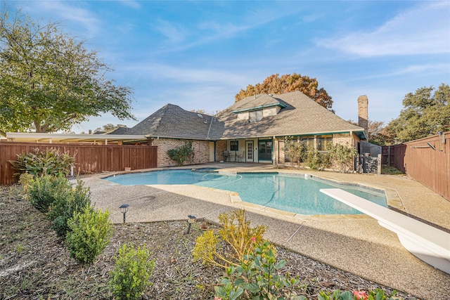 view of swimming pool with a patio area, a fenced backyard, a pool with connected hot tub, and a diving board