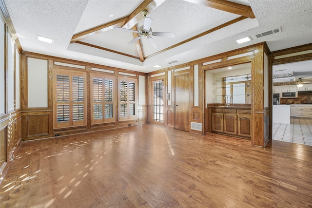 spare room with visible vents, a raised ceiling, ceiling fan, wood finished floors, and a textured ceiling