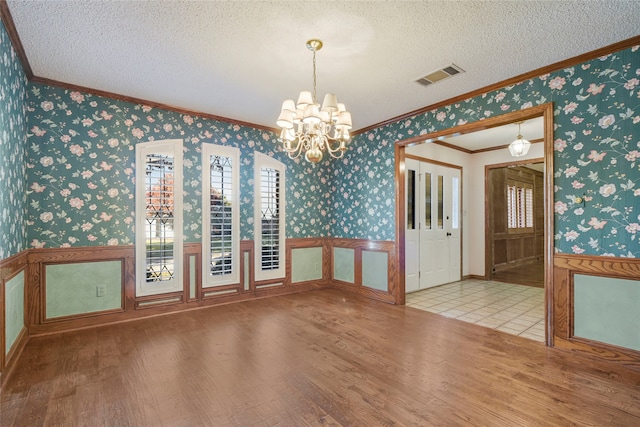 interior space featuring a notable chandelier, ornamental molding, a textured ceiling, and light wood-type flooring