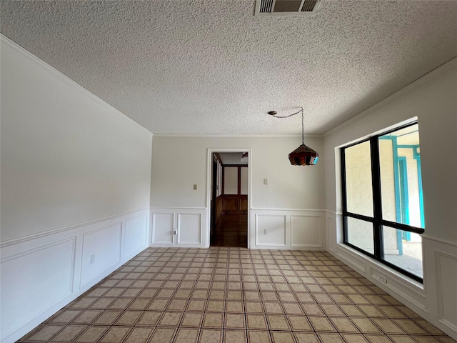 spare room with ornamental molding, a wainscoted wall, visible vents, and a textured ceiling