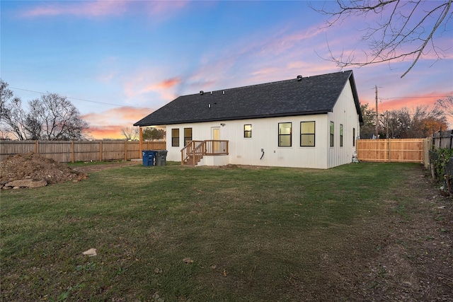 back house at dusk featuring a lawn