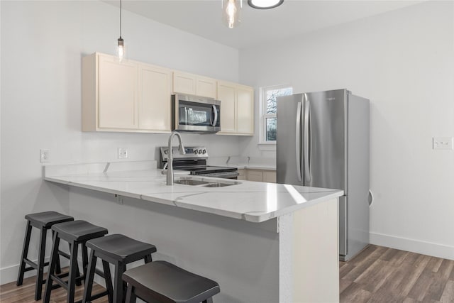 kitchen featuring dark hardwood / wood-style flooring, appliances with stainless steel finishes, decorative light fixtures, and kitchen peninsula