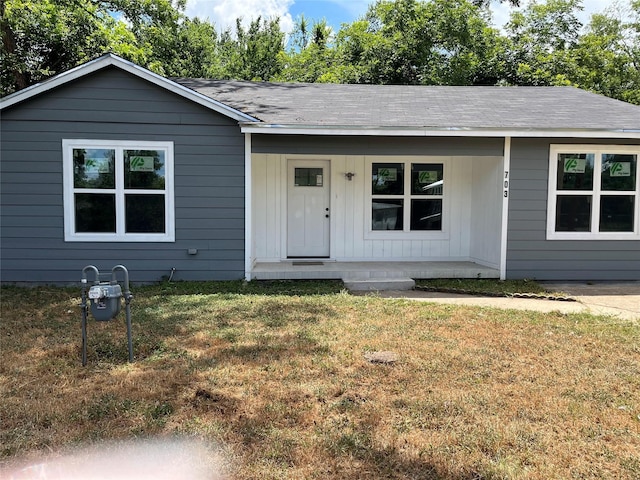 ranch-style house featuring covered porch and a front yard