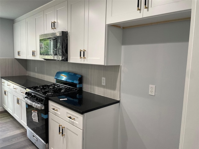 kitchen with white cabinets, appliances with stainless steel finishes, and light hardwood / wood-style flooring