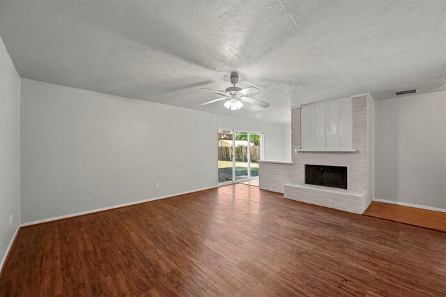 unfurnished living room with ceiling fan, a fireplace, wood-type flooring, and a textured ceiling