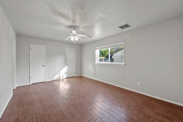 unfurnished room with a textured ceiling, ceiling fan, and dark wood-type flooring