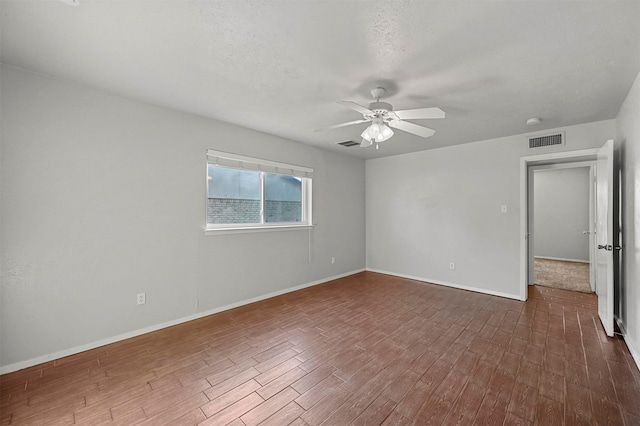 spare room with a textured ceiling, ceiling fan, and dark wood-type flooring