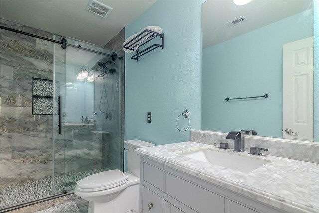 bathroom featuring vanity, a shower with shower door, and toilet