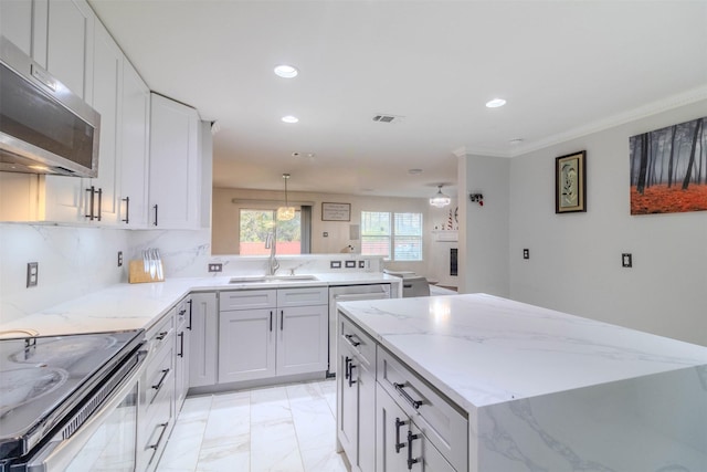 kitchen featuring sink, light stone counters, appliances with stainless steel finishes, kitchen peninsula, and decorative backsplash