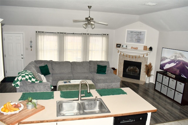 living room featuring sink, dark wood-type flooring, a tile fireplace, ceiling fan, and vaulted ceiling