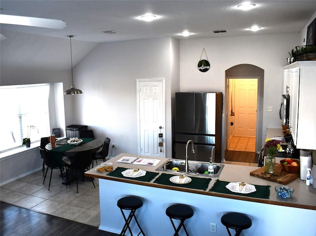 kitchen featuring sink, wood-type flooring, decorative light fixtures, a breakfast bar area, and appliances with stainless steel finishes