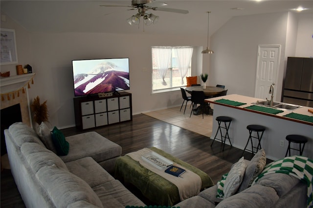 living room featuring vaulted ceiling, ceiling fan, wood-type flooring, and sink