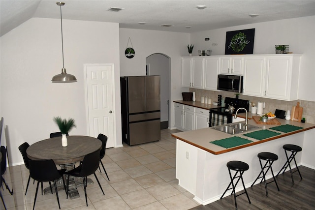 kitchen with appliances with stainless steel finishes, pendant lighting, sink, white cabinets, and decorative backsplash