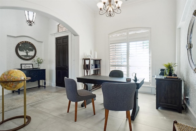 dining area featuring crown molding, a towering ceiling, and a chandelier