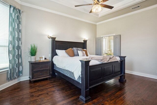 bedroom featuring a tray ceiling, crown molding, ceiling fan, and dark wood-type flooring