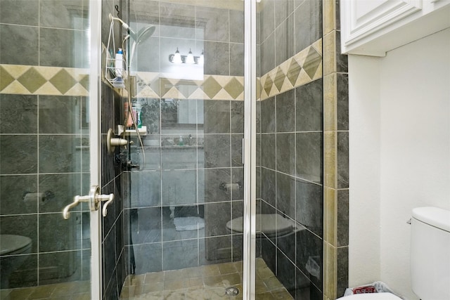 bathroom featuring a shower with door and toilet