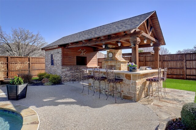 view of patio featuring a gazebo, ceiling fan, an outdoor bar, and an outdoor stone fireplace