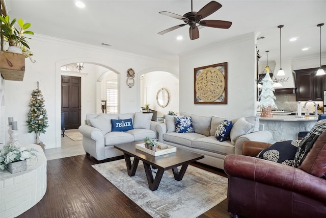 living room featuring dark hardwood / wood-style floors, ceiling fan, and crown molding