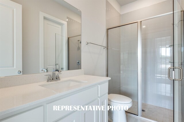 bathroom with tile patterned floors, vanity, toilet, and a shower with shower door