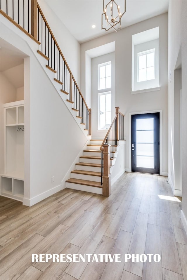 entryway featuring a chandelier, a towering ceiling, and light hardwood / wood-style flooring