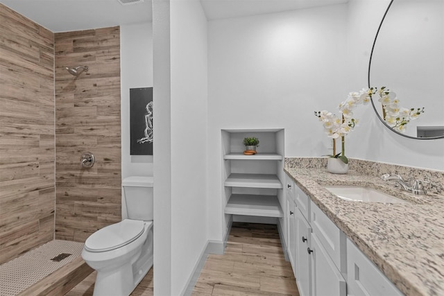 bathroom featuring hardwood / wood-style flooring, vanity, toilet, and a tile shower