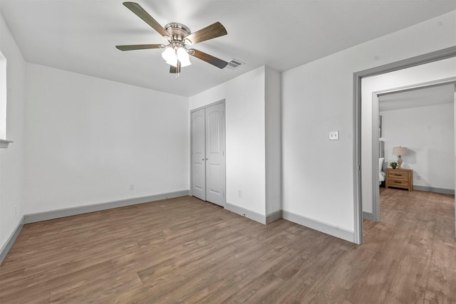 unfurnished bedroom with ceiling fan, a closet, and light hardwood / wood-style floors