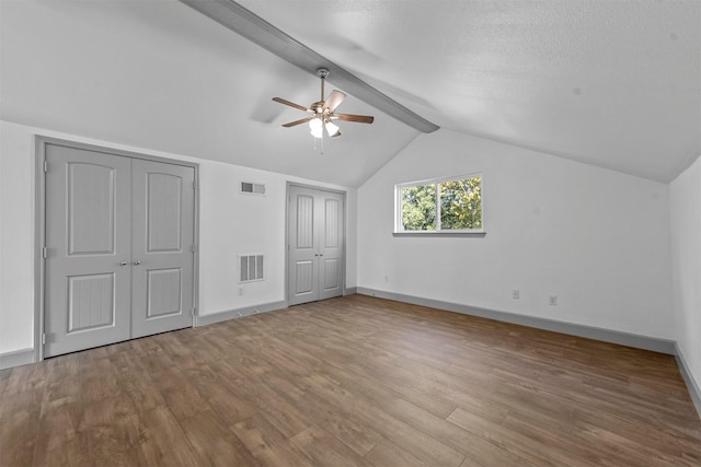 additional living space with ceiling fan, lofted ceiling with beams, and hardwood / wood-style flooring