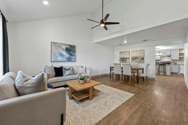 living room with dark hardwood / wood-style floors, ceiling fan, and high vaulted ceiling