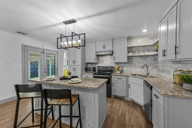 kitchen featuring light stone counters, stainless steel appliances, sink, dark hardwood / wood-style floors, and a kitchen island