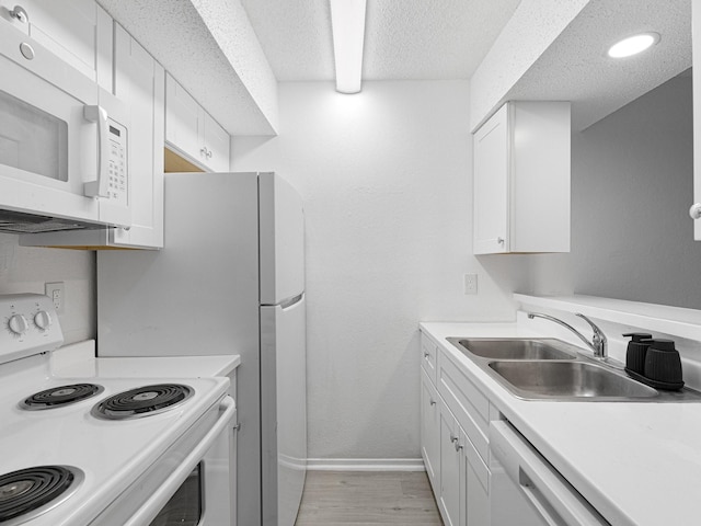 kitchen with white appliances, sink, light hardwood / wood-style flooring, a textured ceiling, and white cabinetry