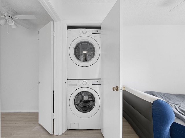 laundry room with a textured ceiling, light wood-type flooring, stacked washing maching and dryer, and ceiling fan