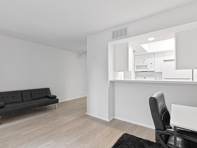 home office with a textured ceiling and light hardwood / wood-style flooring