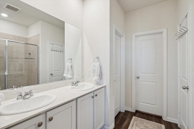 bathroom with hardwood / wood-style floors, vanity, and an enclosed shower