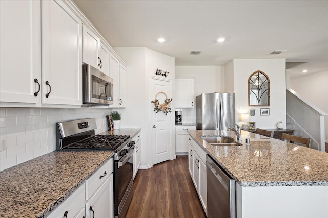 kitchen featuring white cabinetry, decorative backsplash, a kitchen island with sink, and appliances with stainless steel finishes