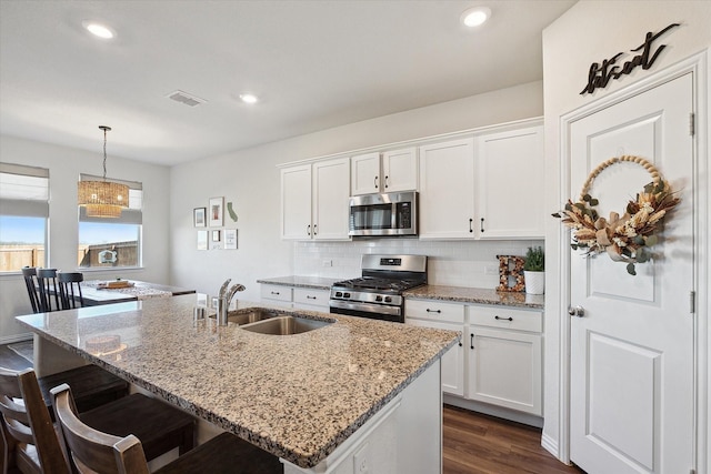 kitchen with sink, white cabinets, stainless steel appliances, and decorative light fixtures