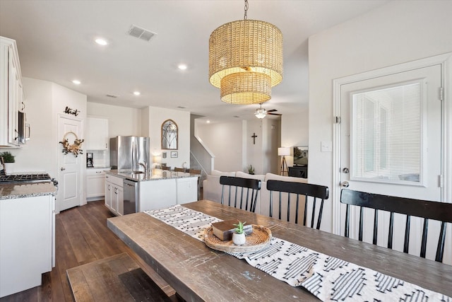 dining area featuring dark hardwood / wood-style flooring, ceiling fan with notable chandelier, and sink