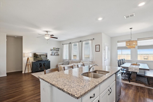 kitchen featuring sink, white cabinets, hanging light fixtures, and a center island with sink