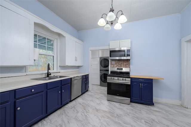 kitchen featuring blue cabinetry, hanging light fixtures, stainless steel appliances, stacked washer and dryer, and white cabinets