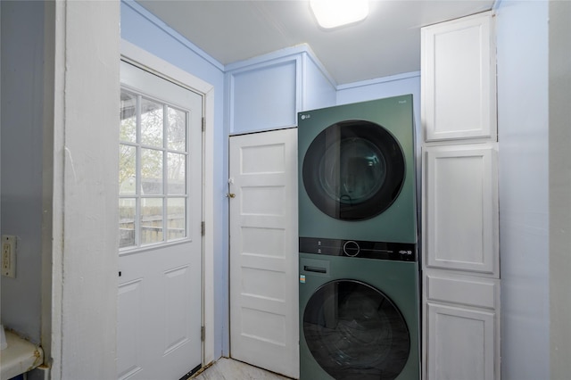 laundry area featuring stacked washer and dryer and cabinets