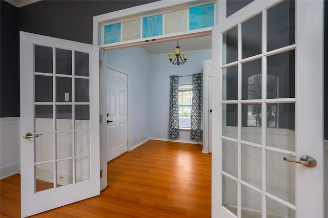 entryway featuring a chandelier, hardwood / wood-style flooring, and crown molding