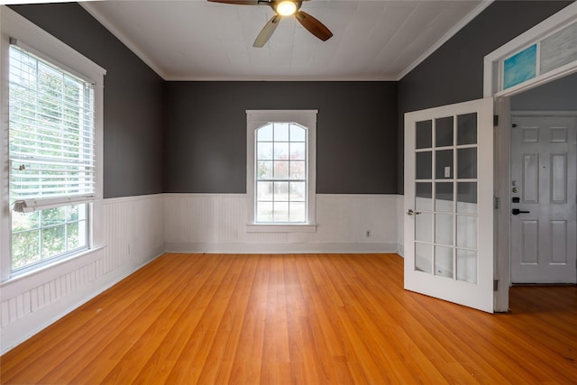 empty room featuring plenty of natural light, light hardwood / wood-style floors, ornamental molding, and ceiling fan