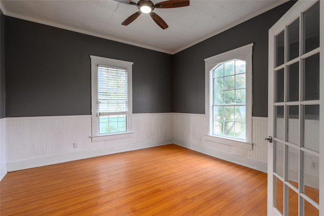 unfurnished room featuring ceiling fan, light wood-type flooring, ornamental molding, and a wealth of natural light