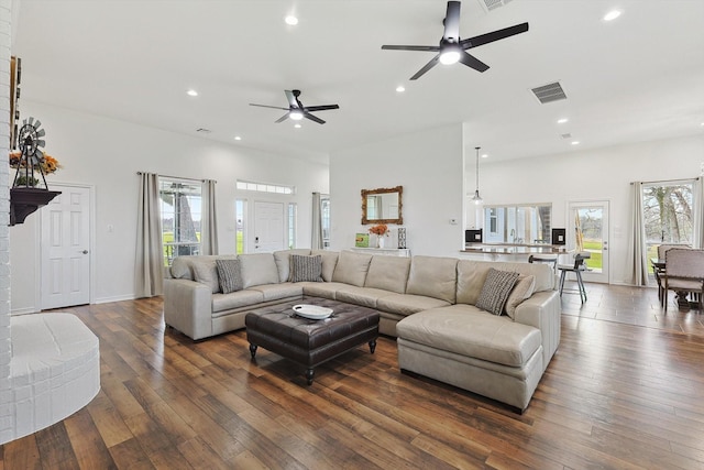 living room featuring dark wood-style flooring, ceiling fan, visible vents, and recessed lighting
