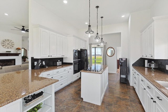 kitchen with a fireplace, a kitchen island, white cabinets, dark stone counters, and black appliances