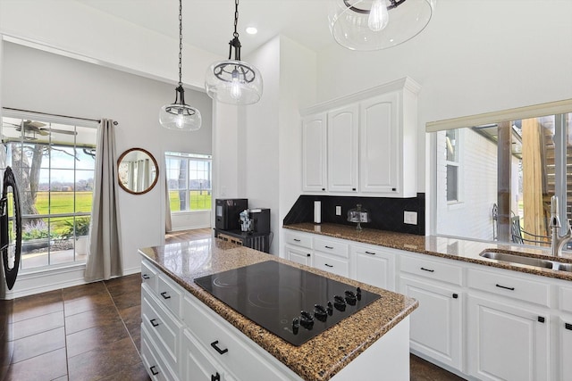 kitchen featuring white cabinetry, black electric cooktop, backsplash, and dark stone counters